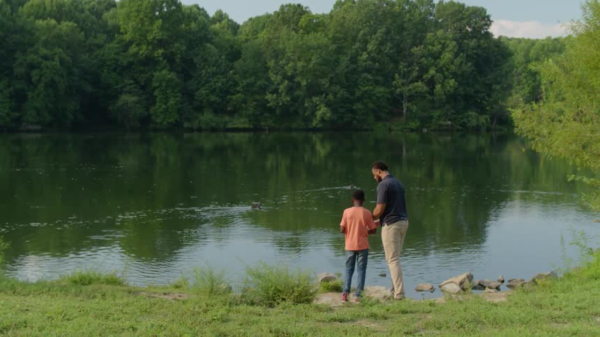 Man and boy fish by a lake in the park