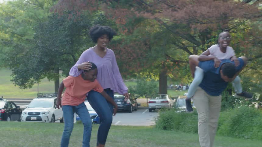 A family laughs while walking in a park