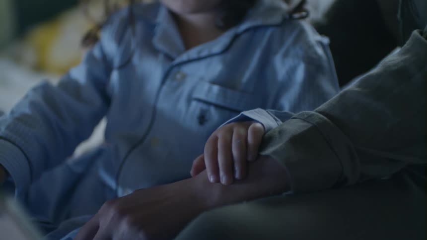 A child and parent sit in bed together
