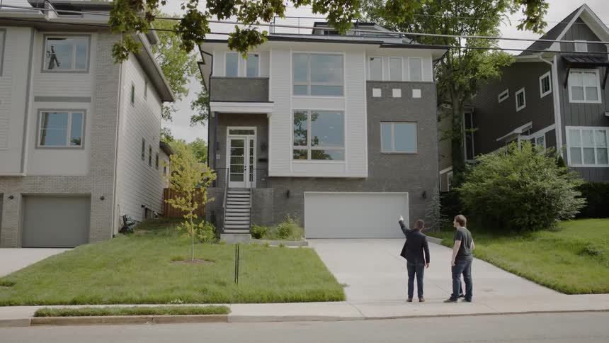 A real estate agent meets a couple to show them a house on suburban street