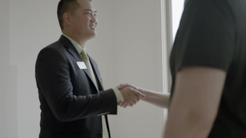 Man shakes hands with man and woman who cuddle each other happily by daytime