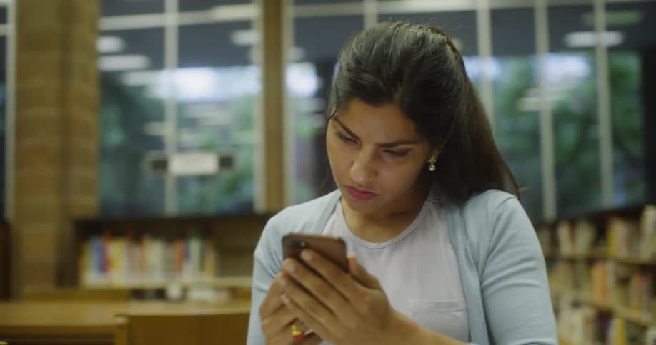 Two women studying something on a phone in the library