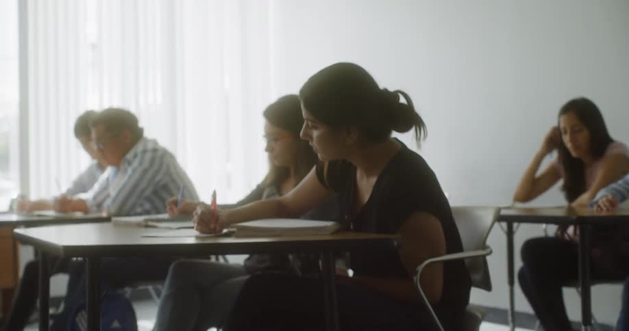 Adults in a classroom taking notes at tables
