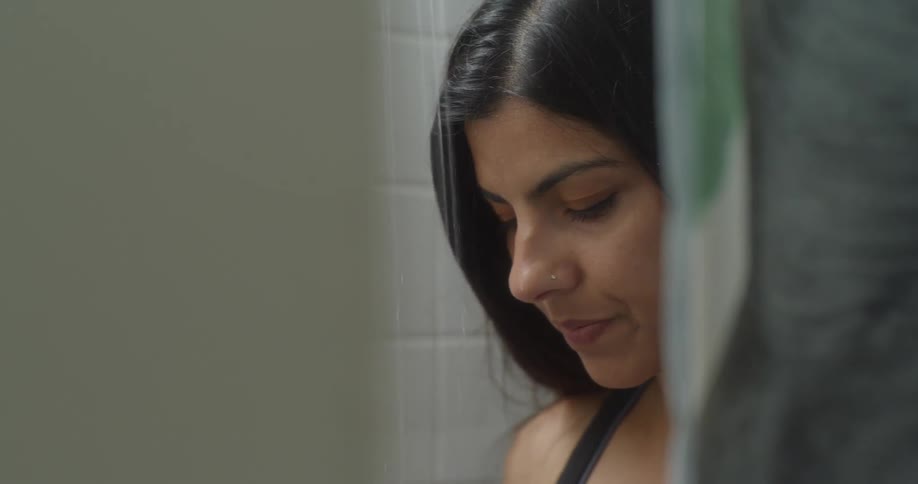 A woman looks sad while taking a shower