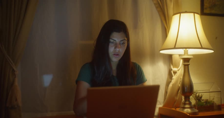 A woman uses a laptop at a dining table at home