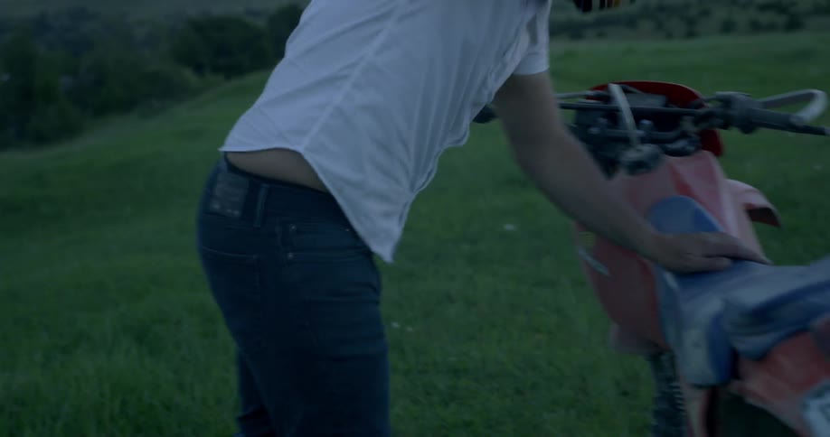 A man is hitting a motorcycle outdoors