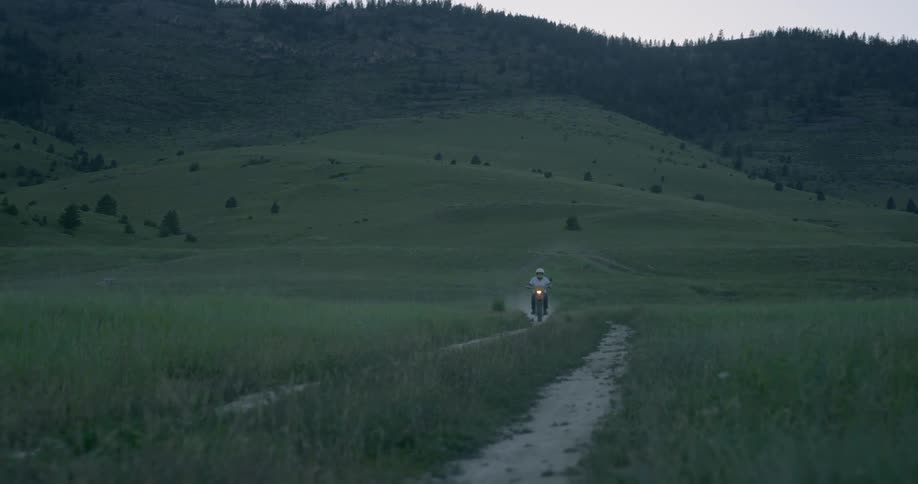 A man on a dirt bikes rides down a path through a field