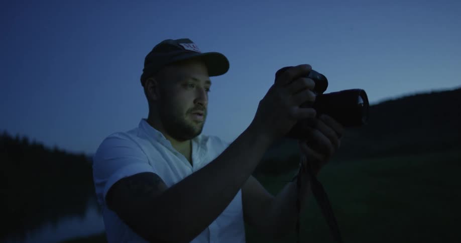 A man looking through his camera at night