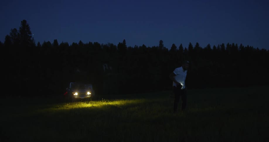 Man is standing outside at night time and walking