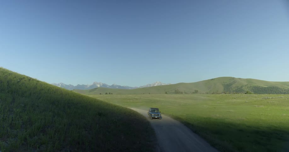 A car is driving on a road in a remote area