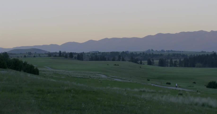 A cyclist travels on a rural road at sunset