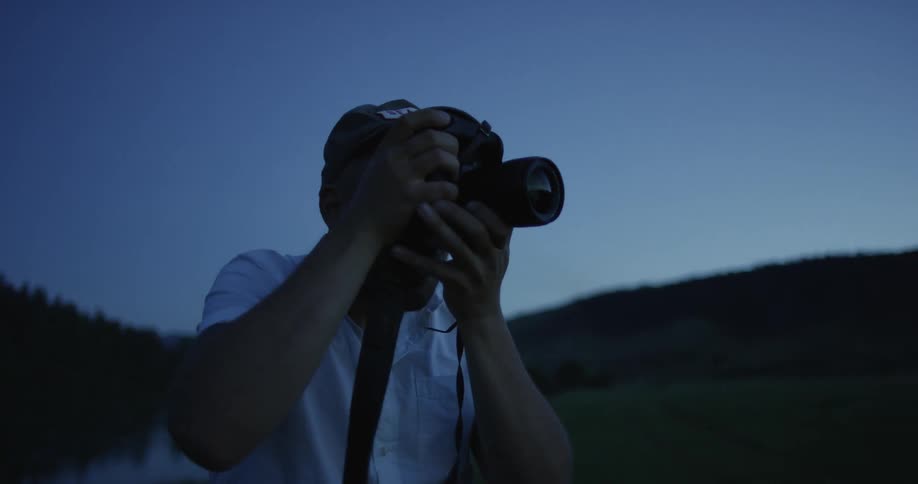 A man is using a camera outdoors at night