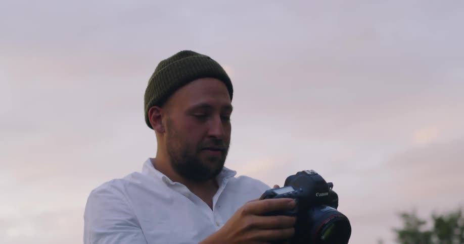 A man using a large canon camera during dusk