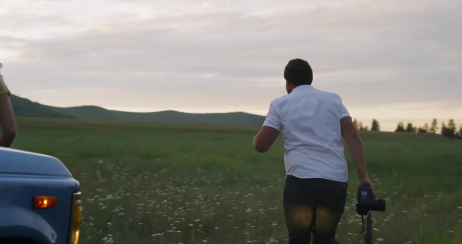 A man photographs women in a rural field at sunset