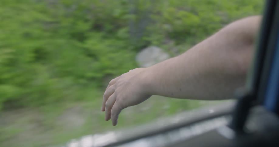 Man has hand out window while driving