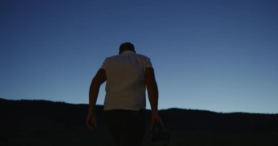 Man walking up a hill during early dawn