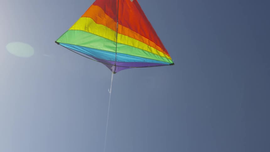 The colors of the spectrum adorn a kite which flies in a blue sky