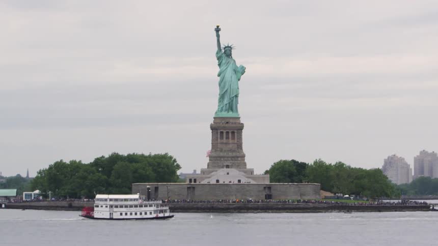 Boats sail through upper new york bay and in front of the statue of liberty