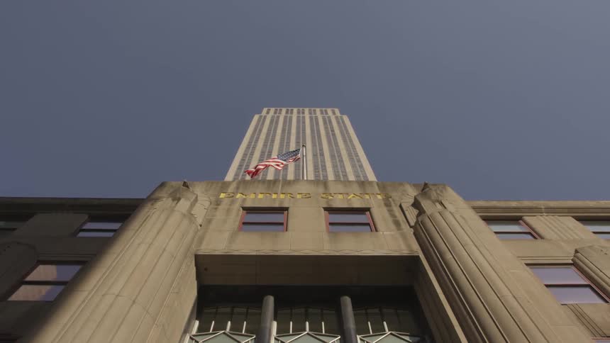 An american flag flutters near the base of a huge building