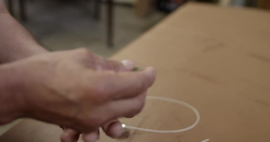 A man's hand feeds some string through a loop on a button