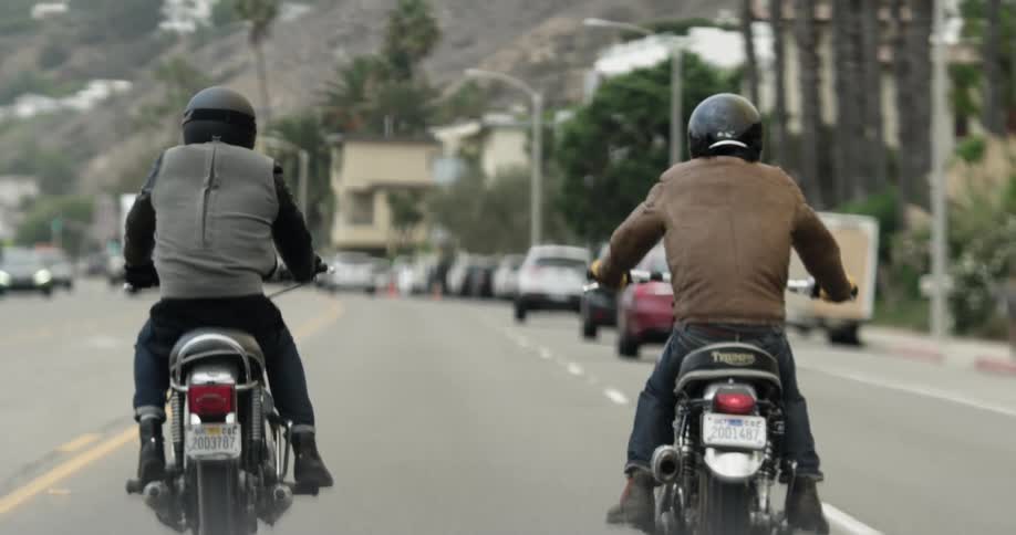 Two motorcyclists writing on a busy city street