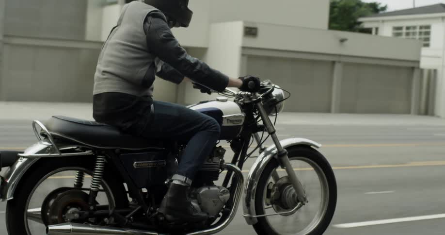 A man rides a motorcycle along a small city's street
