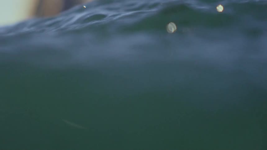 Sea ripples at the bottom of the rock while sun lights sparkles on water surface