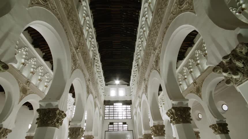 Ornate arched columns in a building lead to windows high on a wall