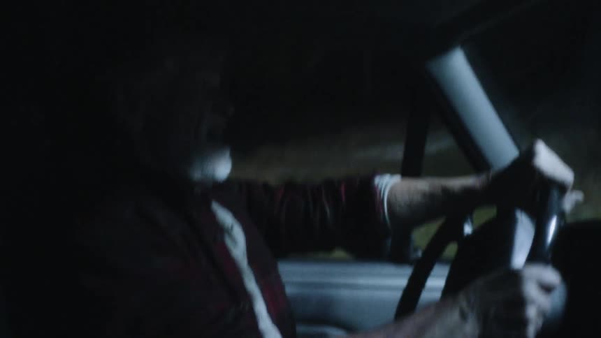 Profile shot of old man driving truck and coming to a stop at night