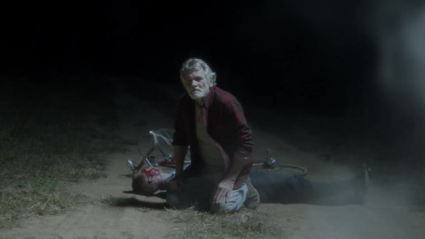 A man sits over a hurt person at night