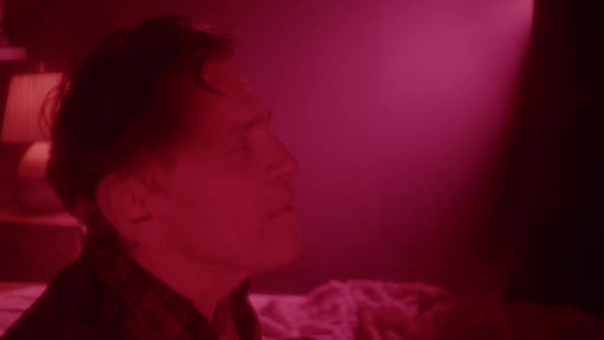 A man quickly sits up in bed and starts talking