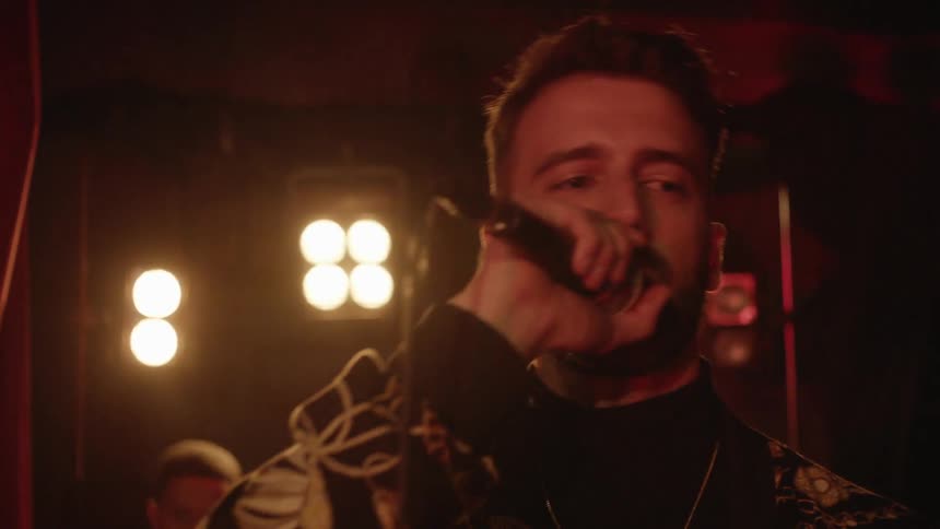 A bearded man sings into a microphone