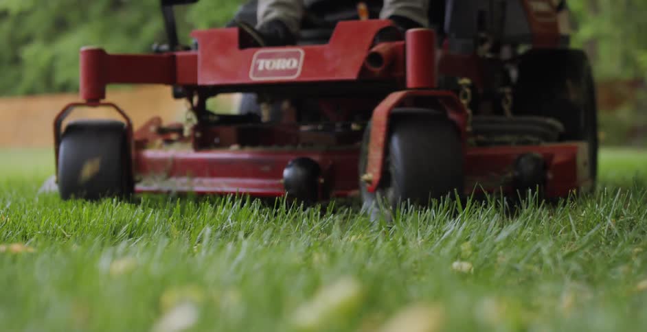 A person rides a lawnmower in the yard