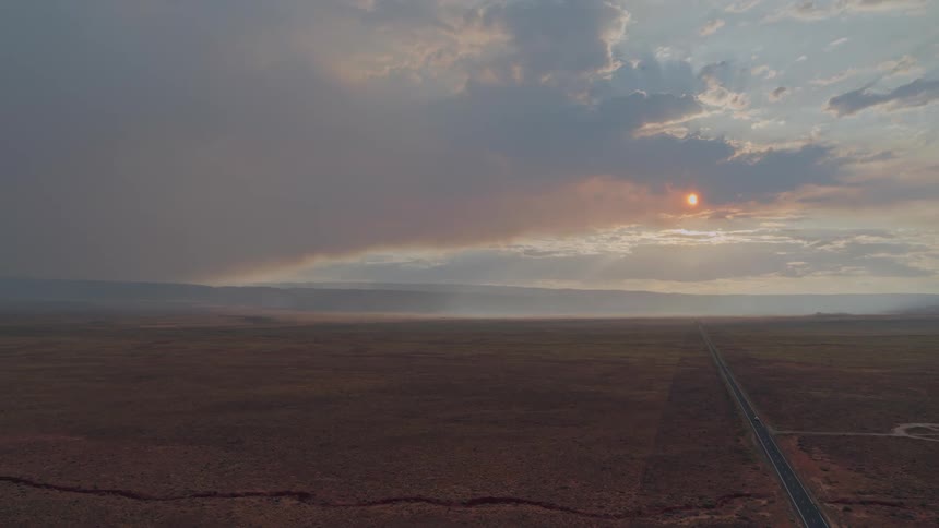Sun sets behind clouds on wasteland