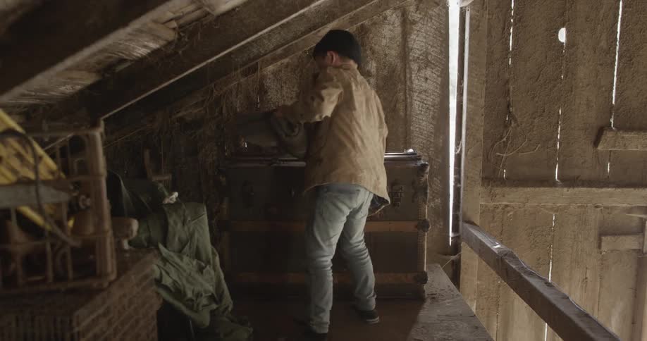 A boy walks over to a trunk and opens it