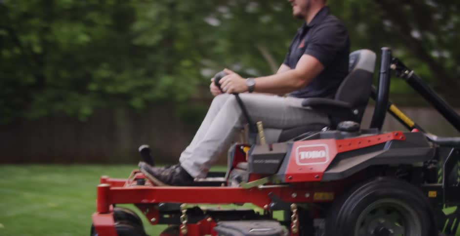 A man on a riding mower in a large fenced in yard