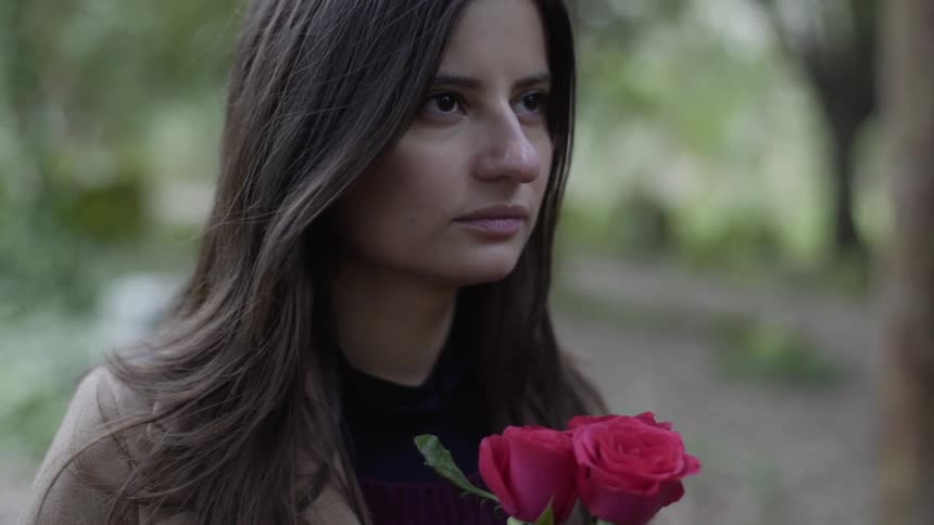 A sad woman holding flowers