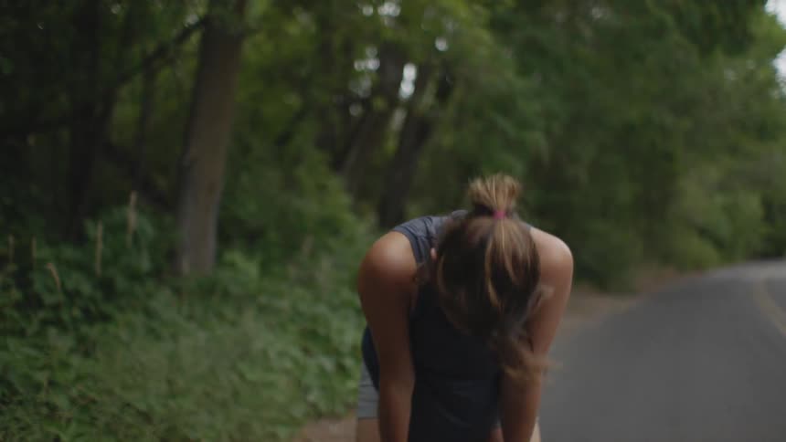 A woman leans down resting by the road
