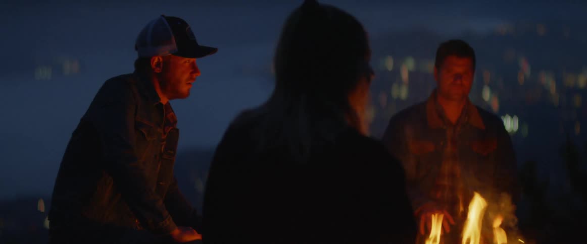 People standing around a campfire with embers flying