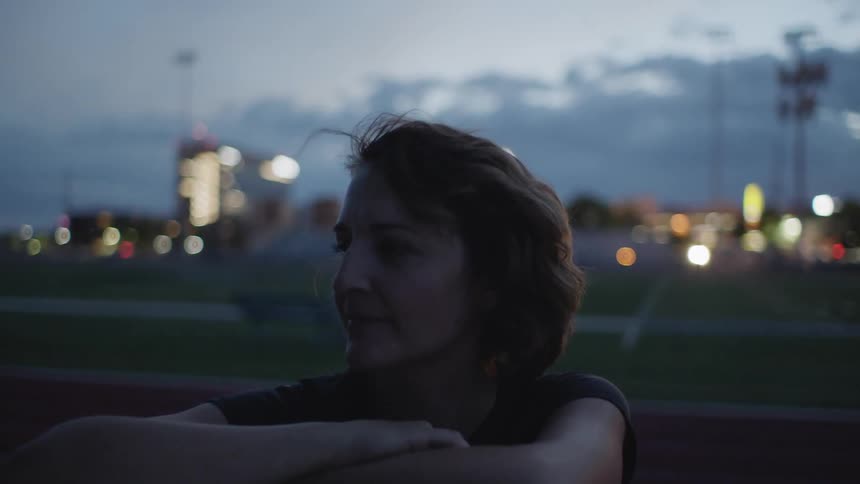 A woman sits outside at dusk