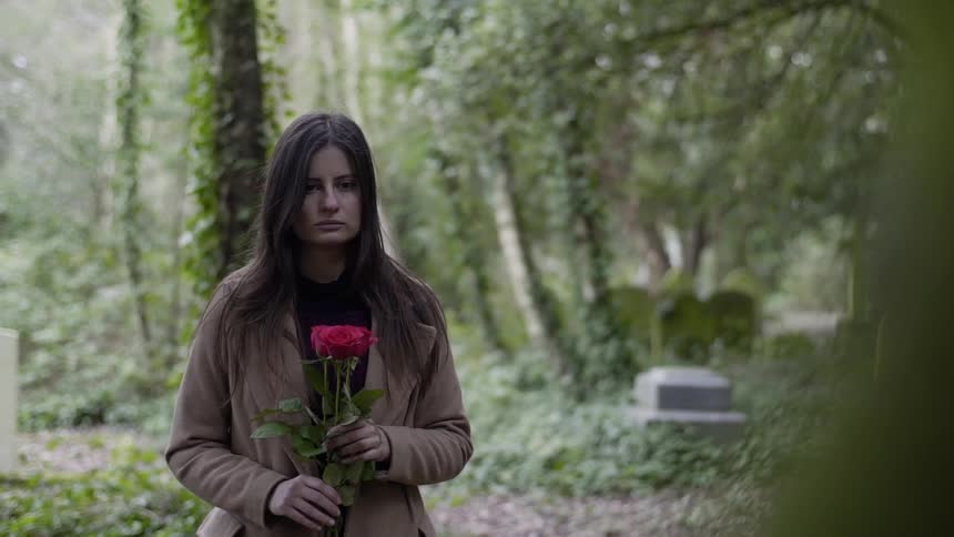 A woman holding flowers in a cemetery