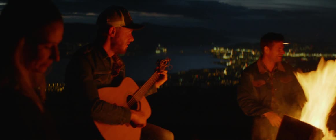 Man plays guitar by campfire