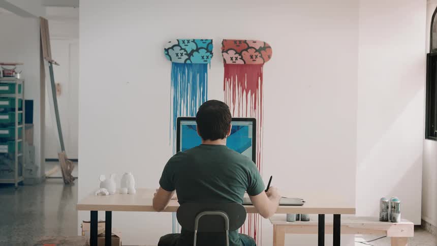 Man sits at desk working on digital art on computer