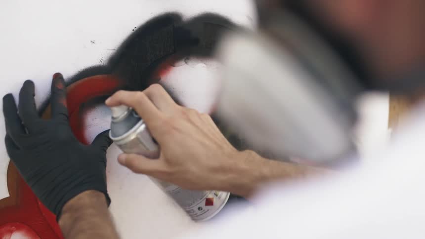 Man paints mural with black spray paint