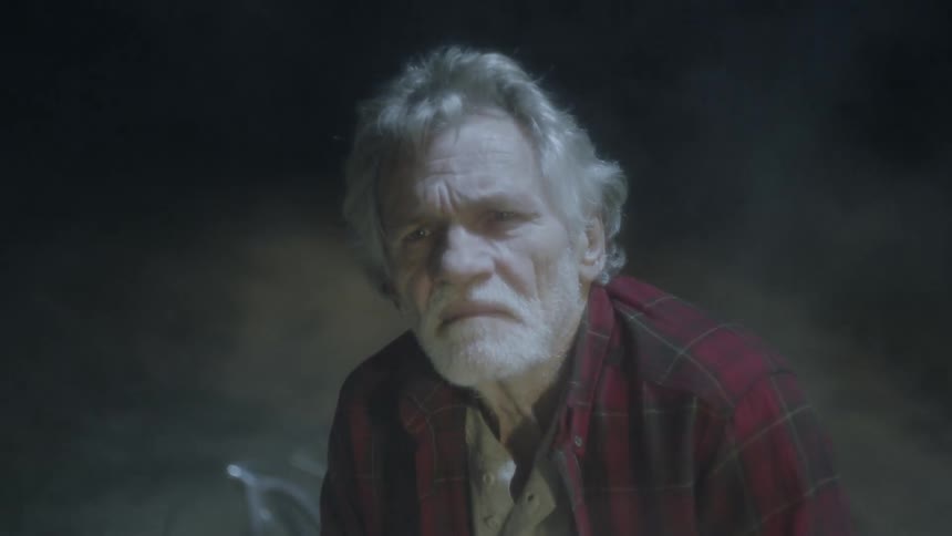 A man is sitting down outdoors at night