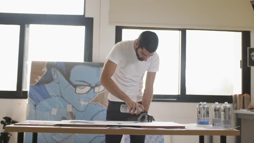 A man is using spray paint while wearing one glove