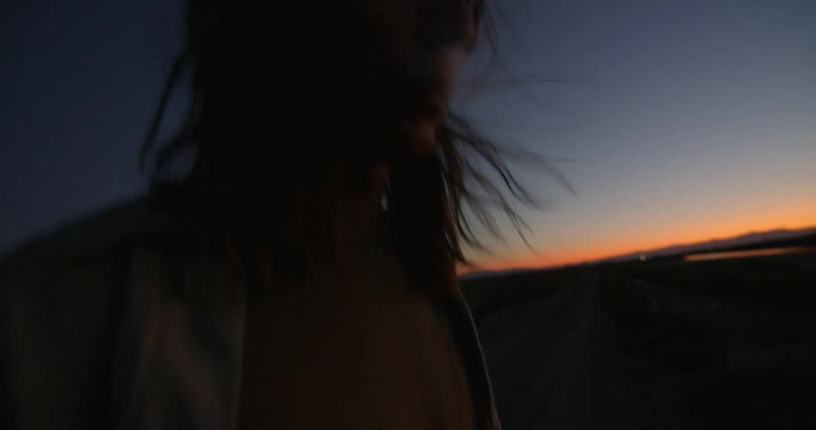 A woman is smoking on the beach at dawn