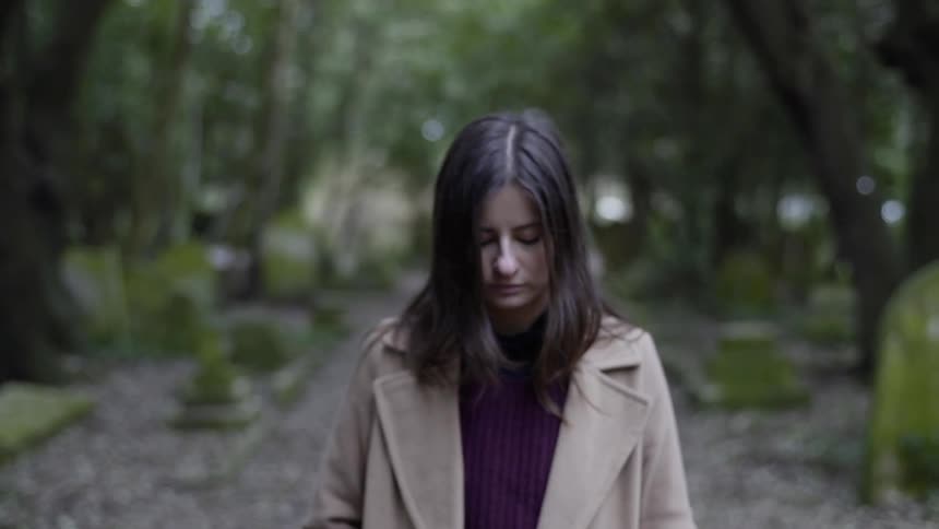 A woman walks in the park looking down