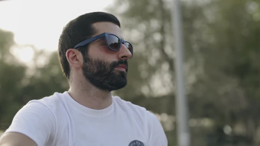 A man is wearing sunglasses as he rides down the street