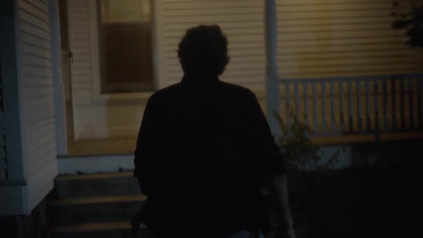 Older man walks up the steps of a home before walking around to enter the side